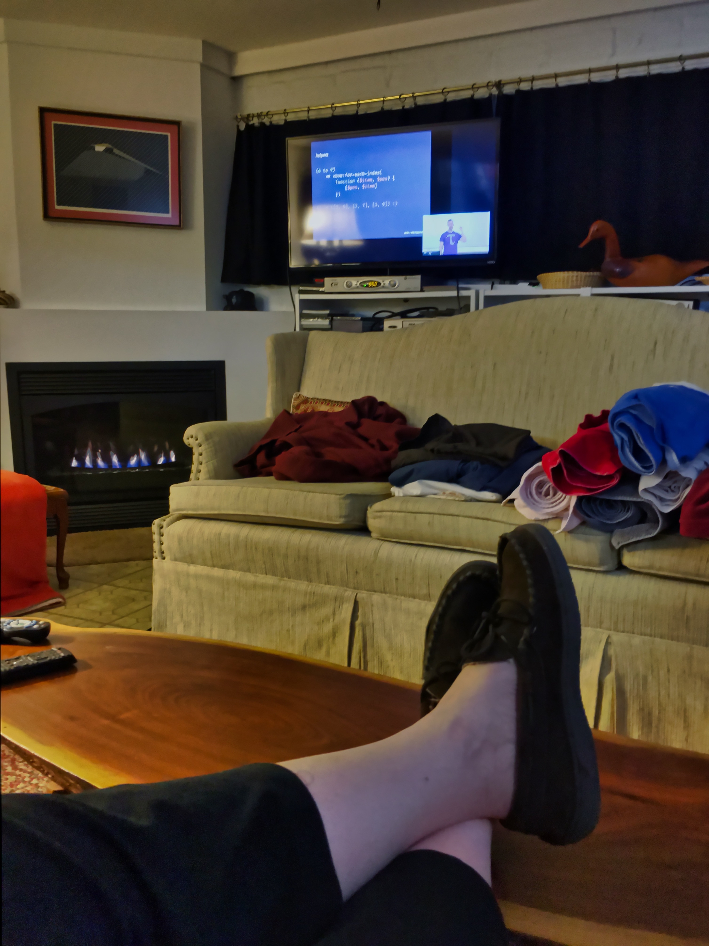 feet up on low table with screen showing conference speaker